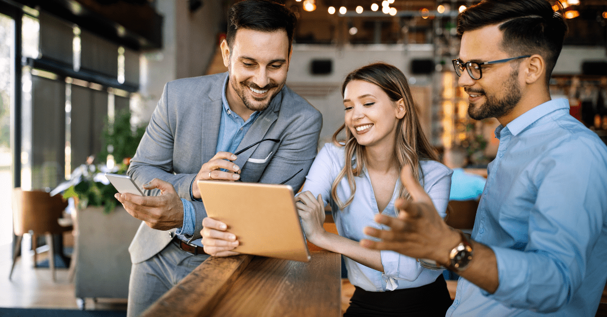 Three workers looking at ipad and smiling