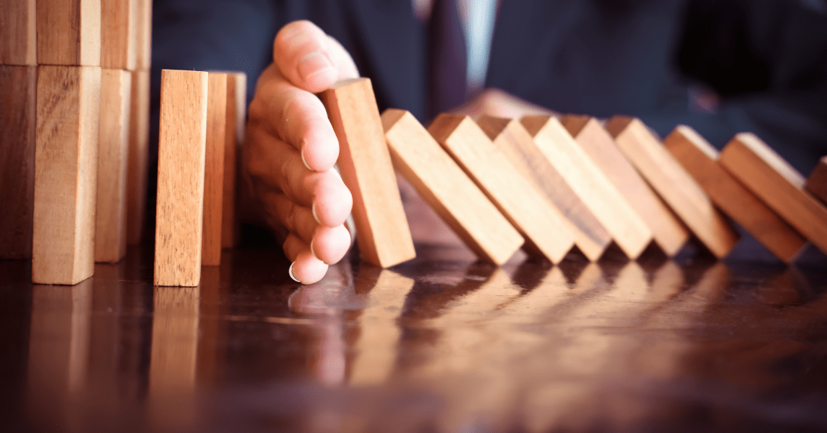 Hand holding blocks to stop them from having a domino effect