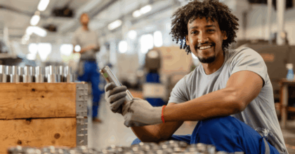 Industrial employee at work wearing gloves, smiling at camera