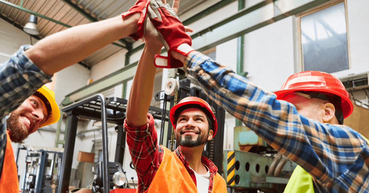 Three light industrial workers clasping hands