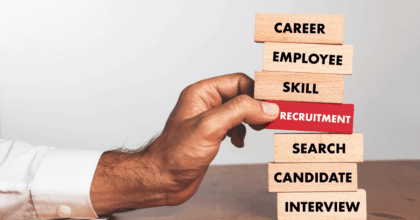 Stack of blocks with one red one that says "Recruitment." Hand grabbing it from the stack.