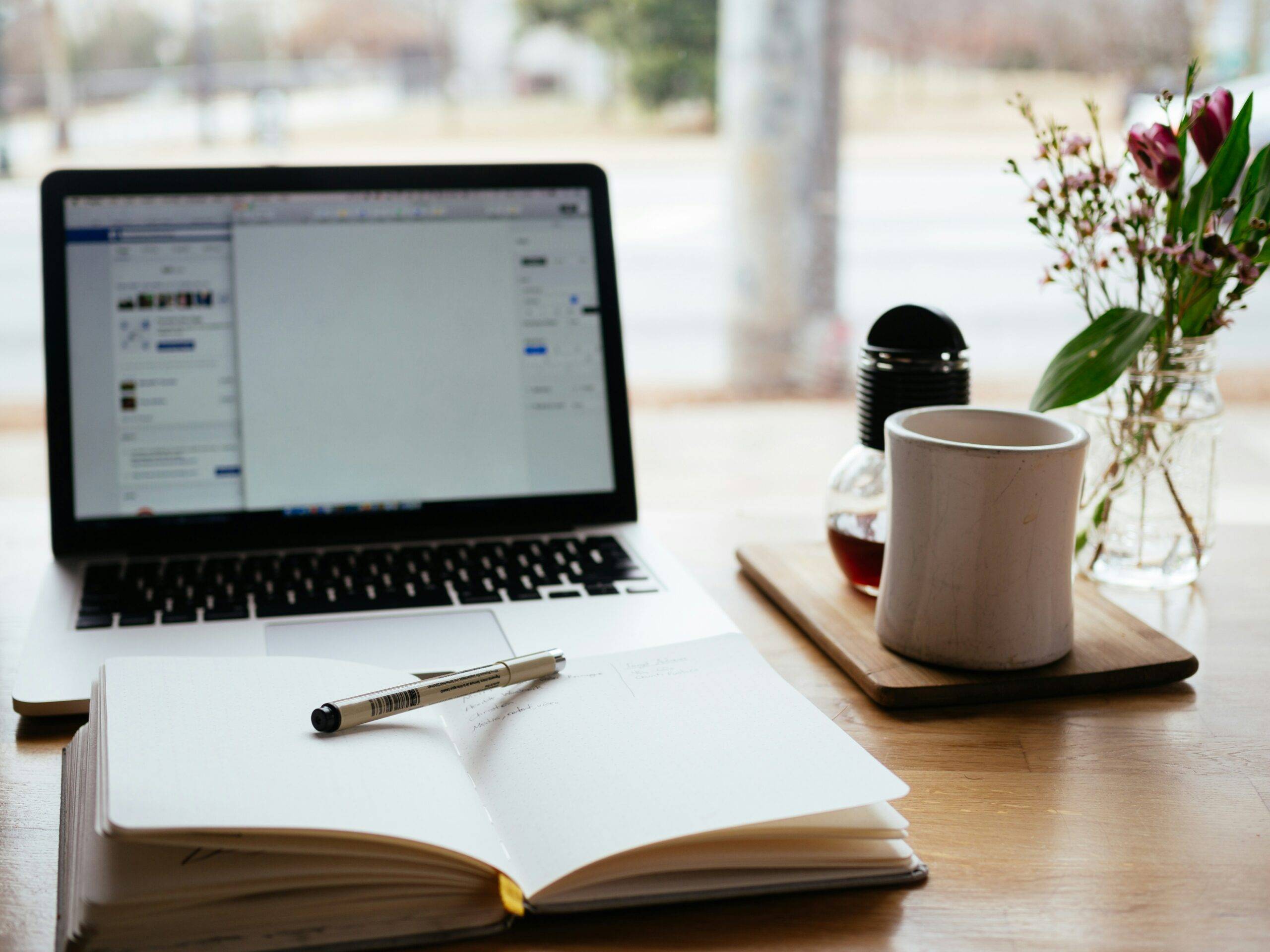 Laptop, notebook, and coffee cup on table